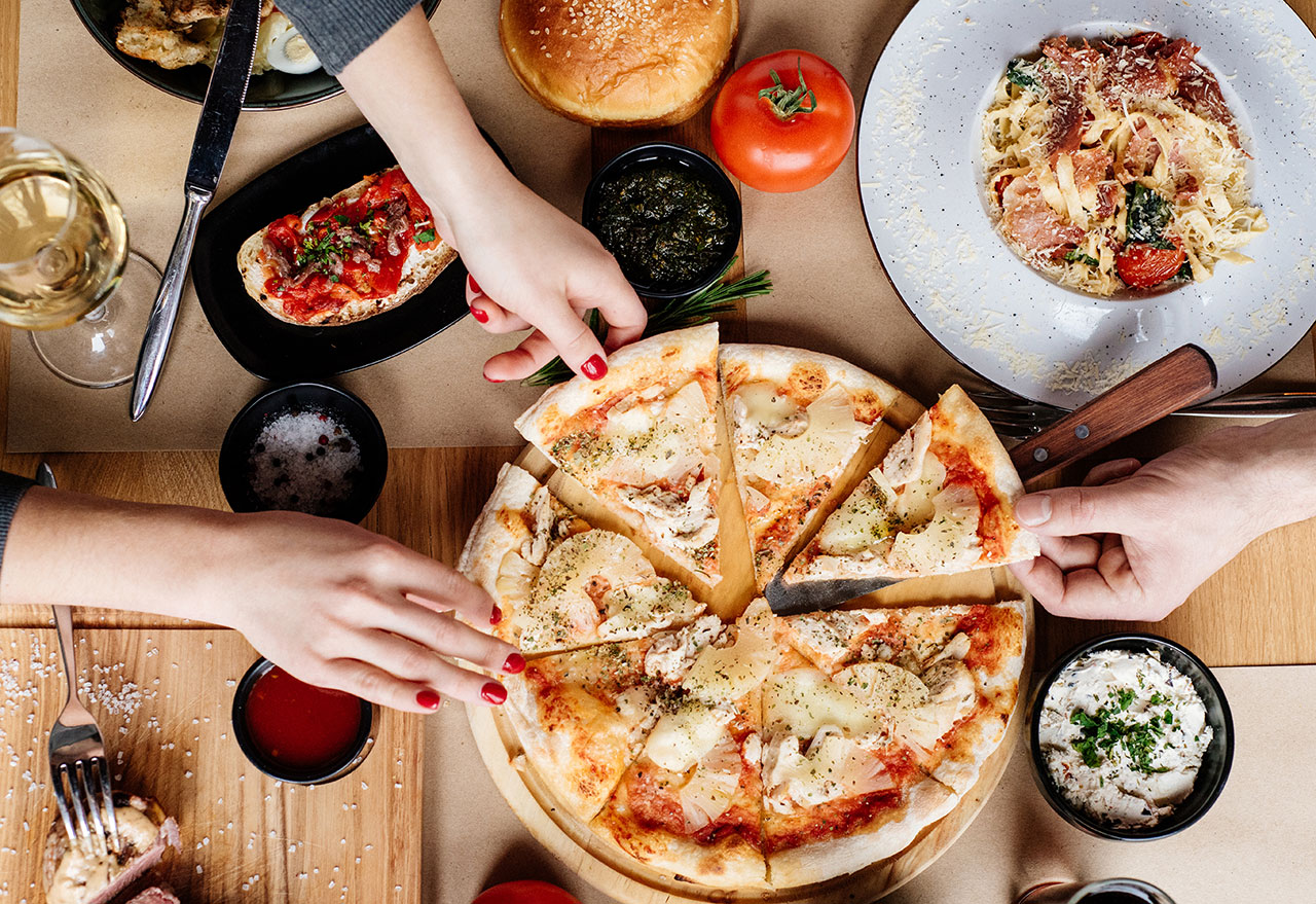 two people sharing pizza, pasta, and bruschetta