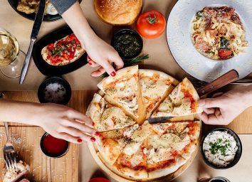 two people sharing pizza, pasta, and bruschetta