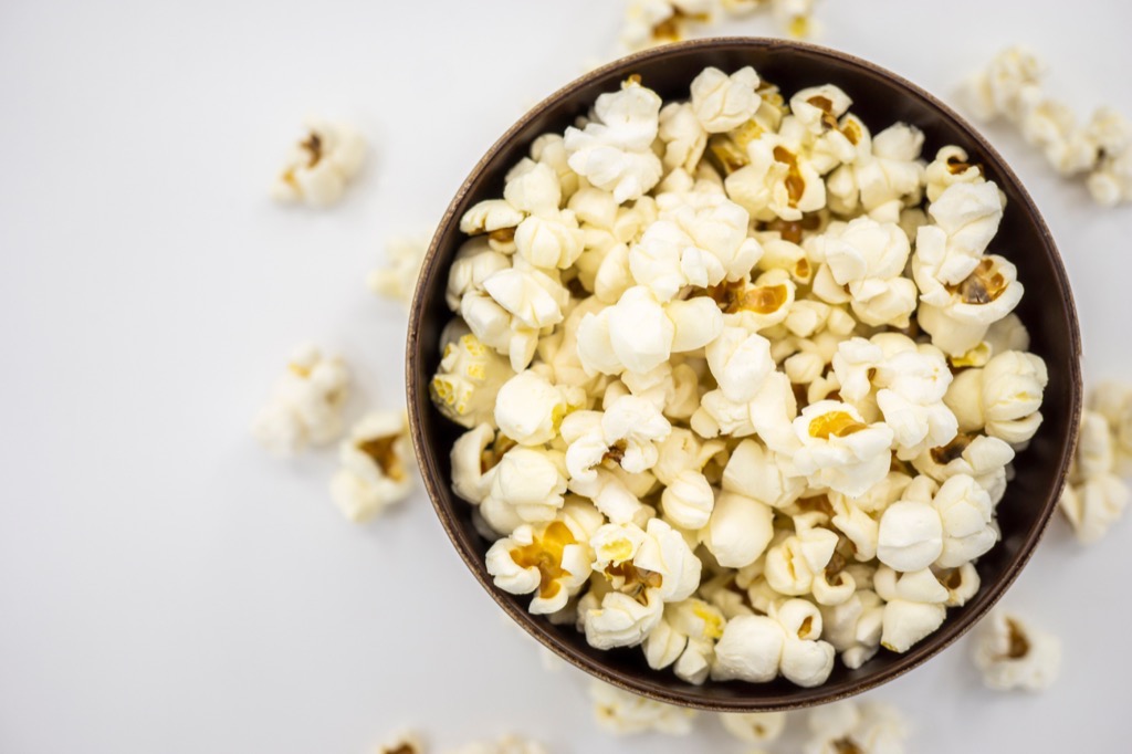 popcorn in wooden bowl on white background