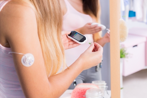 Young sick girl with insulin pump injection on arm