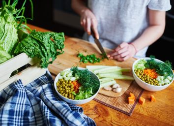 Woman chopping up vegetables to make plant based vegetarian bowl