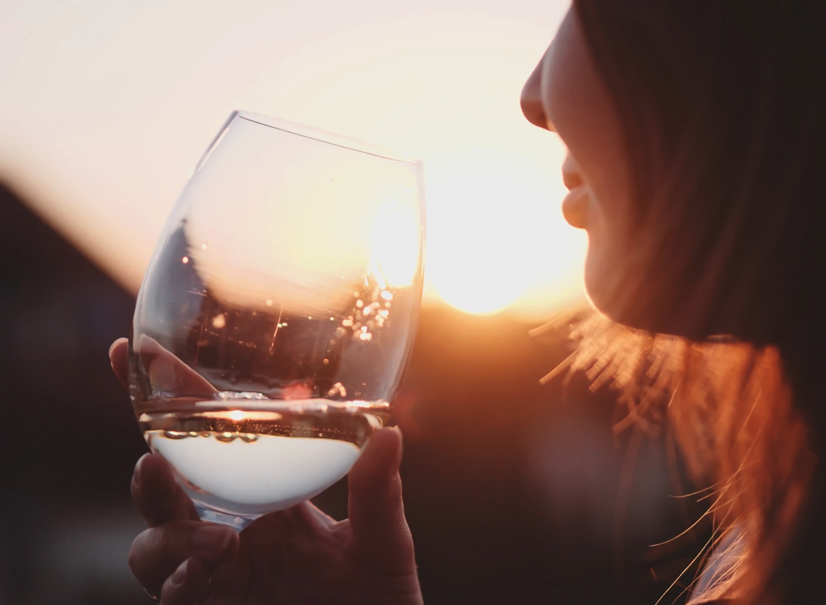 Woman drinking white wine at sunset