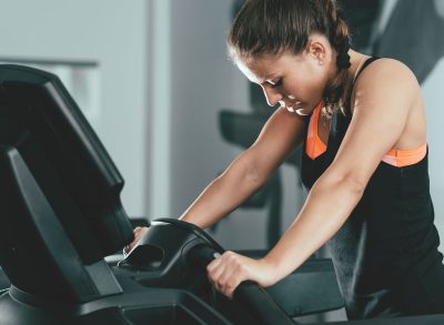 Tired woman at gym struggling to finish treadmill workout