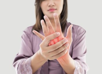 Asian woman suffering from pain in bone against gray background