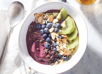 acai bowl with blueberries and kiwi in white bowl with spoon