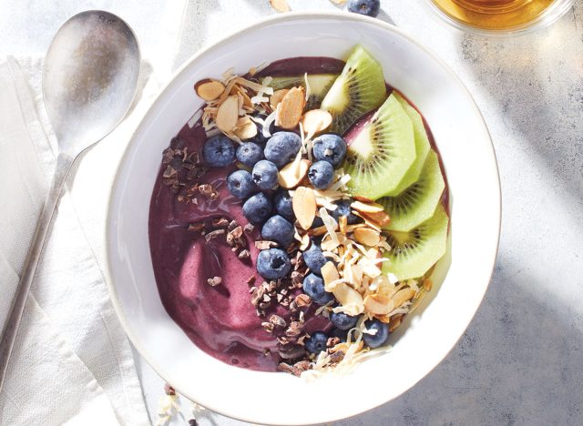 acai bowl with blueberries and kiwi in white bowl with spoon
