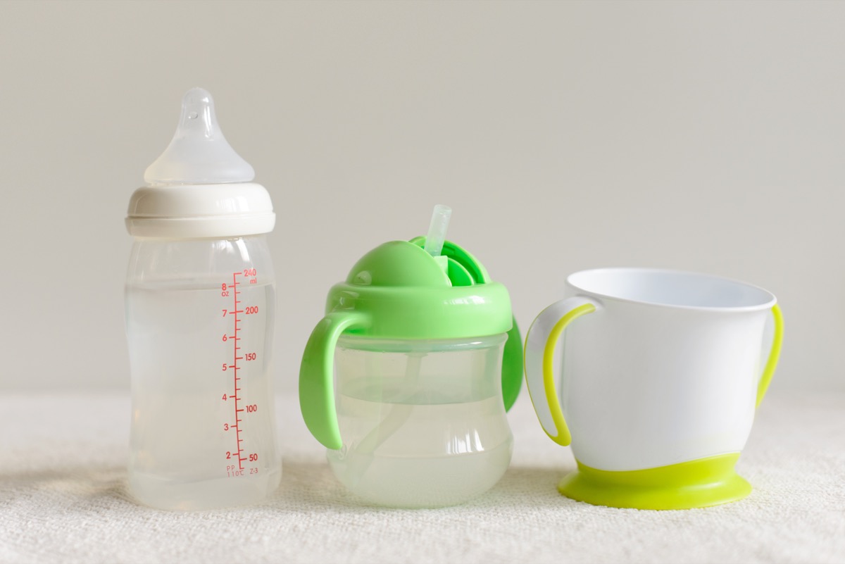 Three kinds of bottles and cups with water for baby