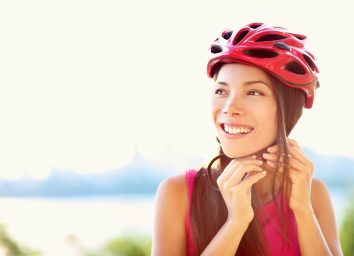 woman putting biking helmet on outside during bicycle ride