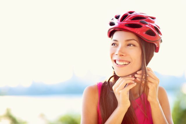 woman putting biking helmet on outside during bicycle ride