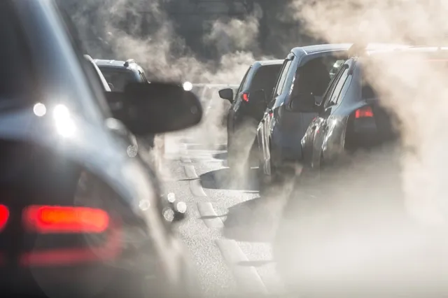 Blurred silhouette of a car surrounded by steam from the exhaust pipe