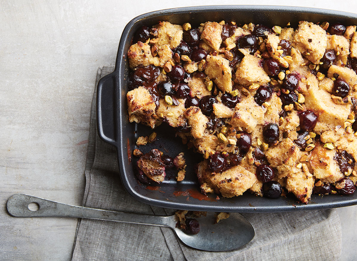 chocolate cherry bread pudding with pistachios in baking tray with spoon