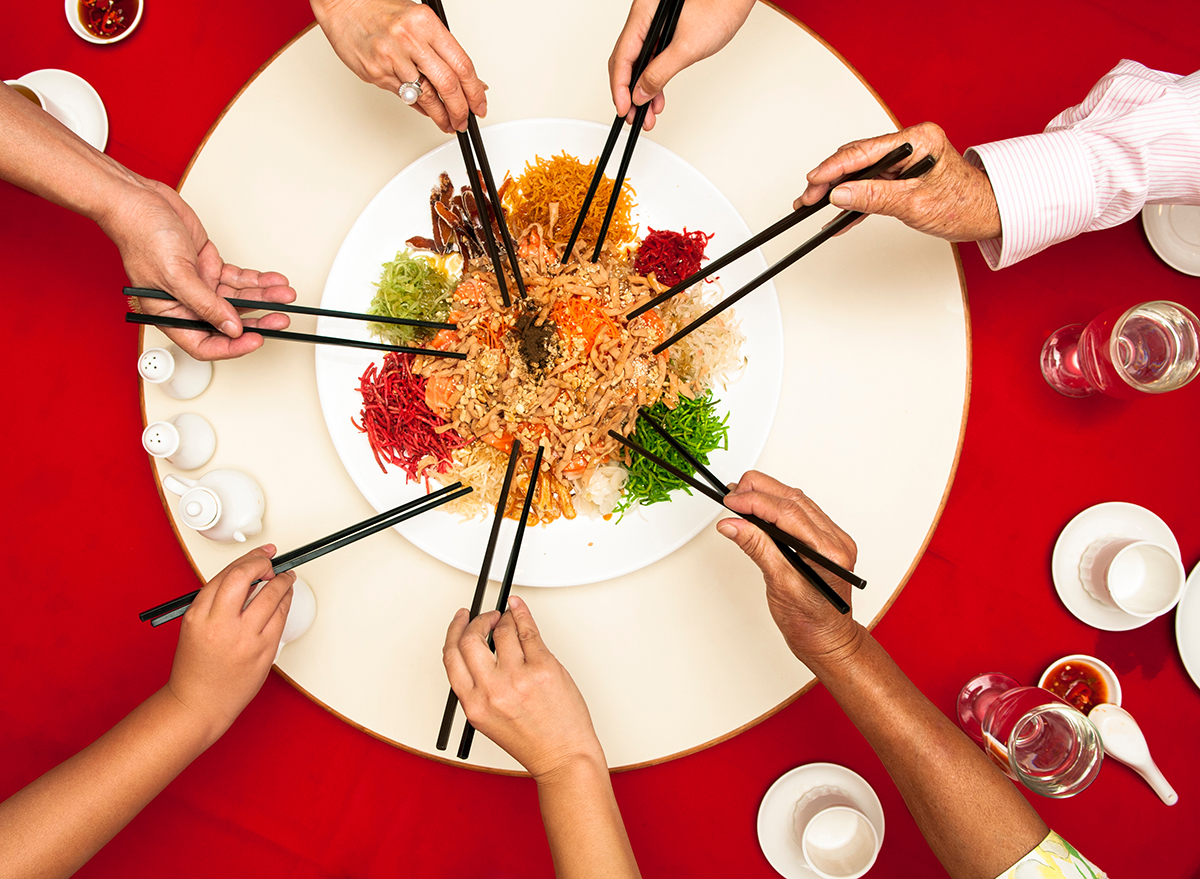 seven people using chopsticks at a red table
