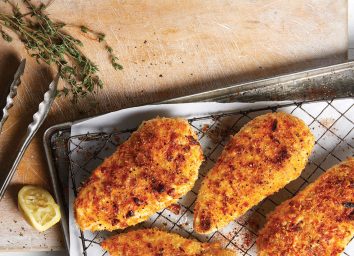 crispy chicken on pan with tongs and lemon