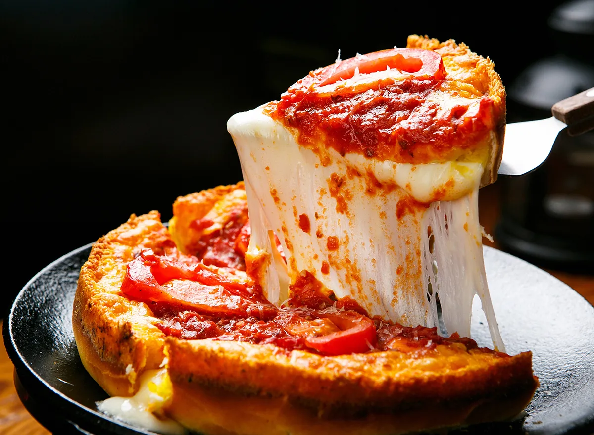 slice of deep dish pizza lifted out of pizza pan in chicago