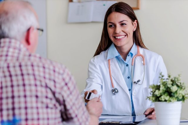 Older patient at woman doctor office paying exam with credit card