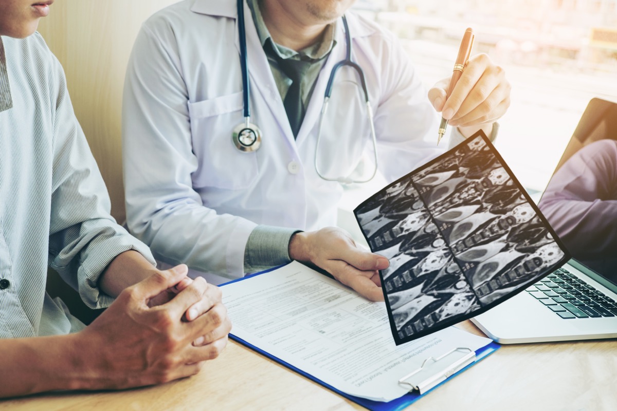 Doctor consulting with patient presenting results on x-ray film