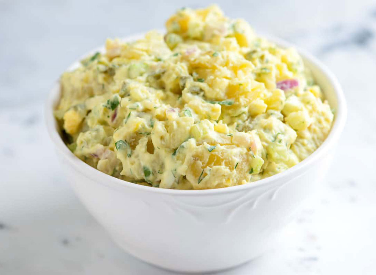 potato salad in white bowl on marble background