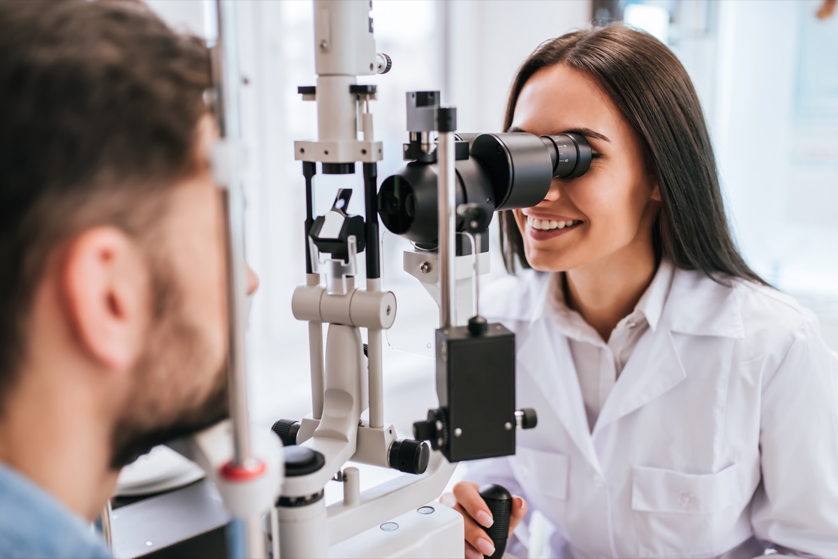 female doctor ophthalmologist is checking the eye vision of handsome young man in modern clinic