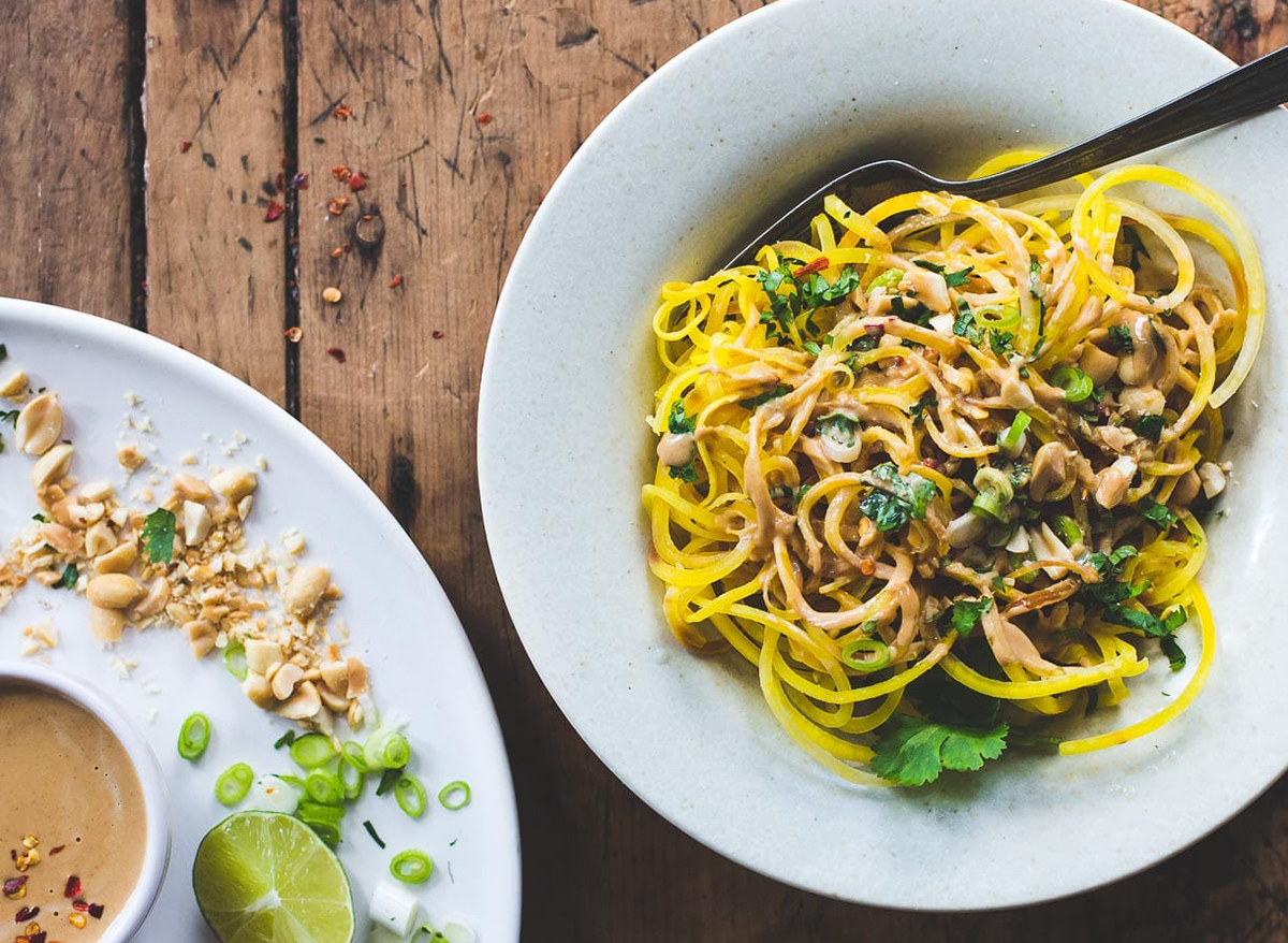 golden beet noodles with peanut sauce in a bowl with herbs