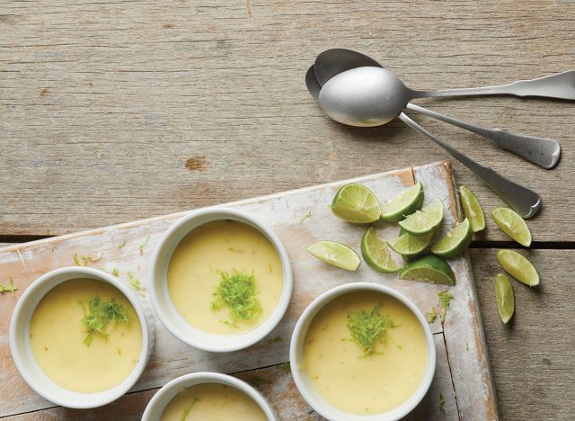 individual bowls of key lime cheesecake on serving tray with lime slices and spoons
