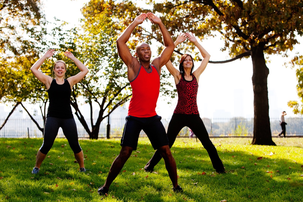 A group of people doing jumping jacks in the park