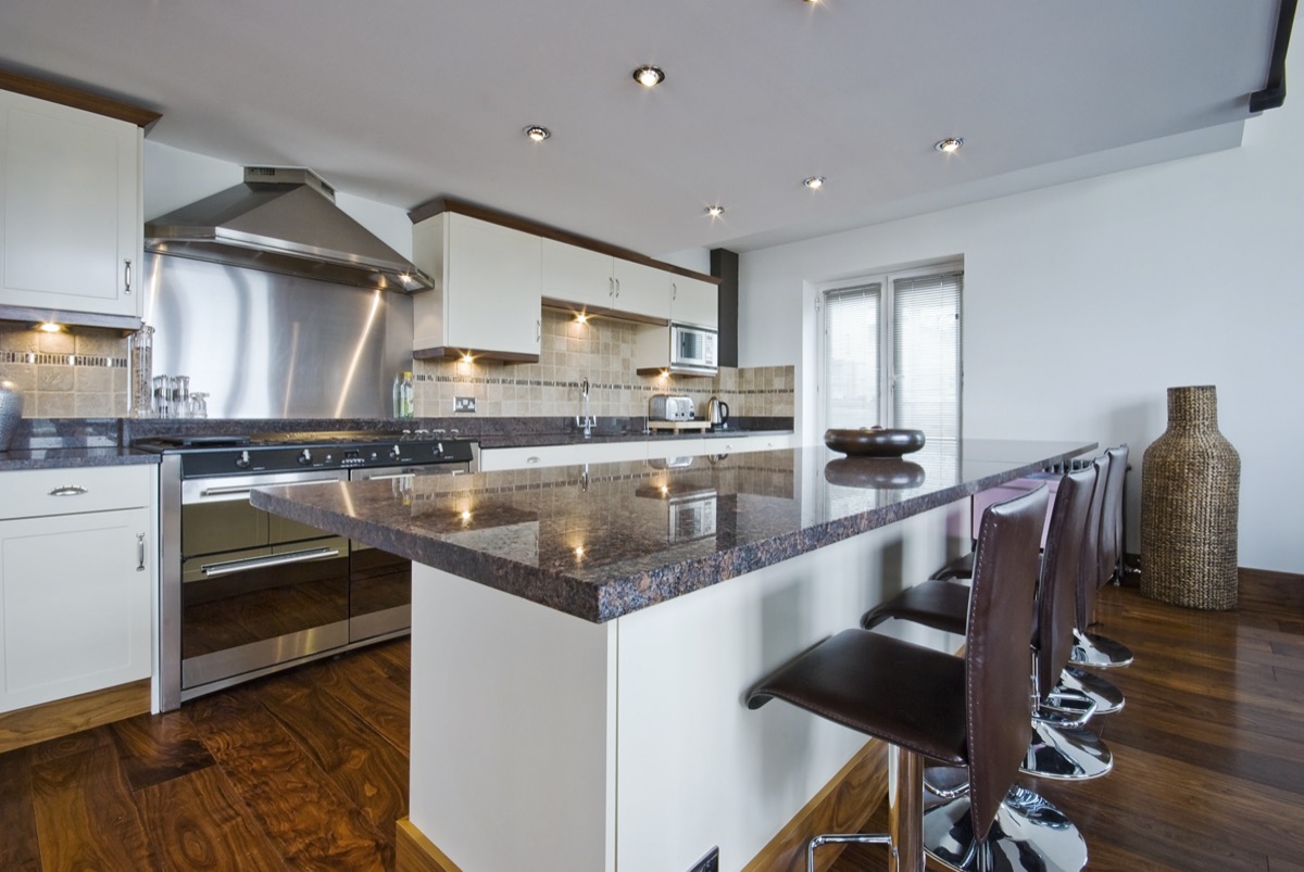 contemporary kitchen with a breakfast bar and polished stone work top.