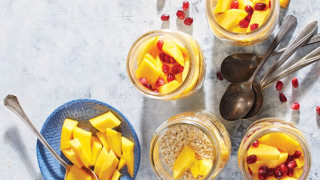 mango ginger overnight oat jars with spoons and pomegranate seeds