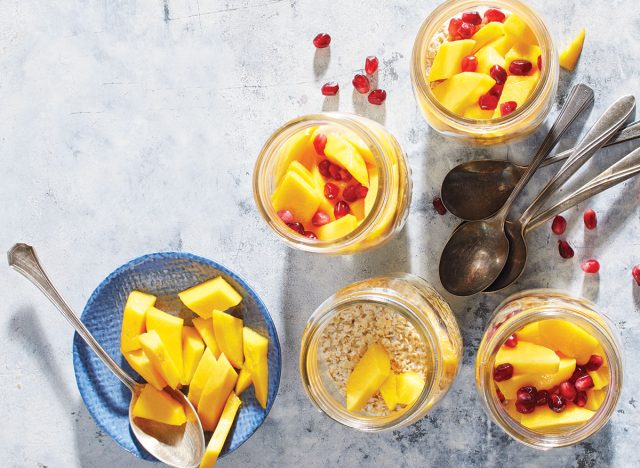 jars of mango ginger night oats with spoons and pomegranate seeds