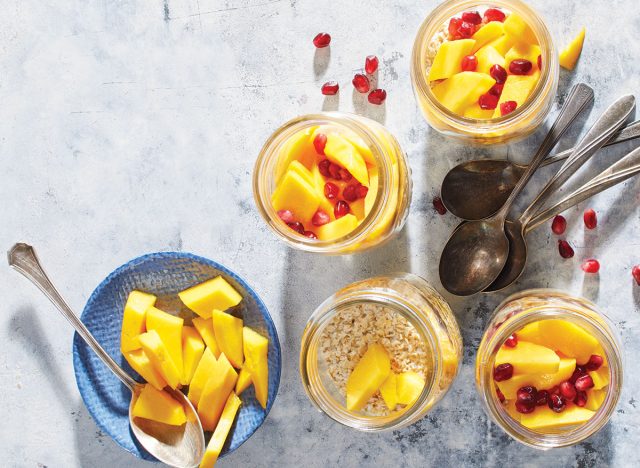 mango ginger overnight oat jars with spoons and pomegranate seeds
