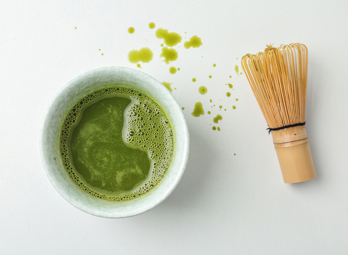 matcha green tea with whisk on white countertop