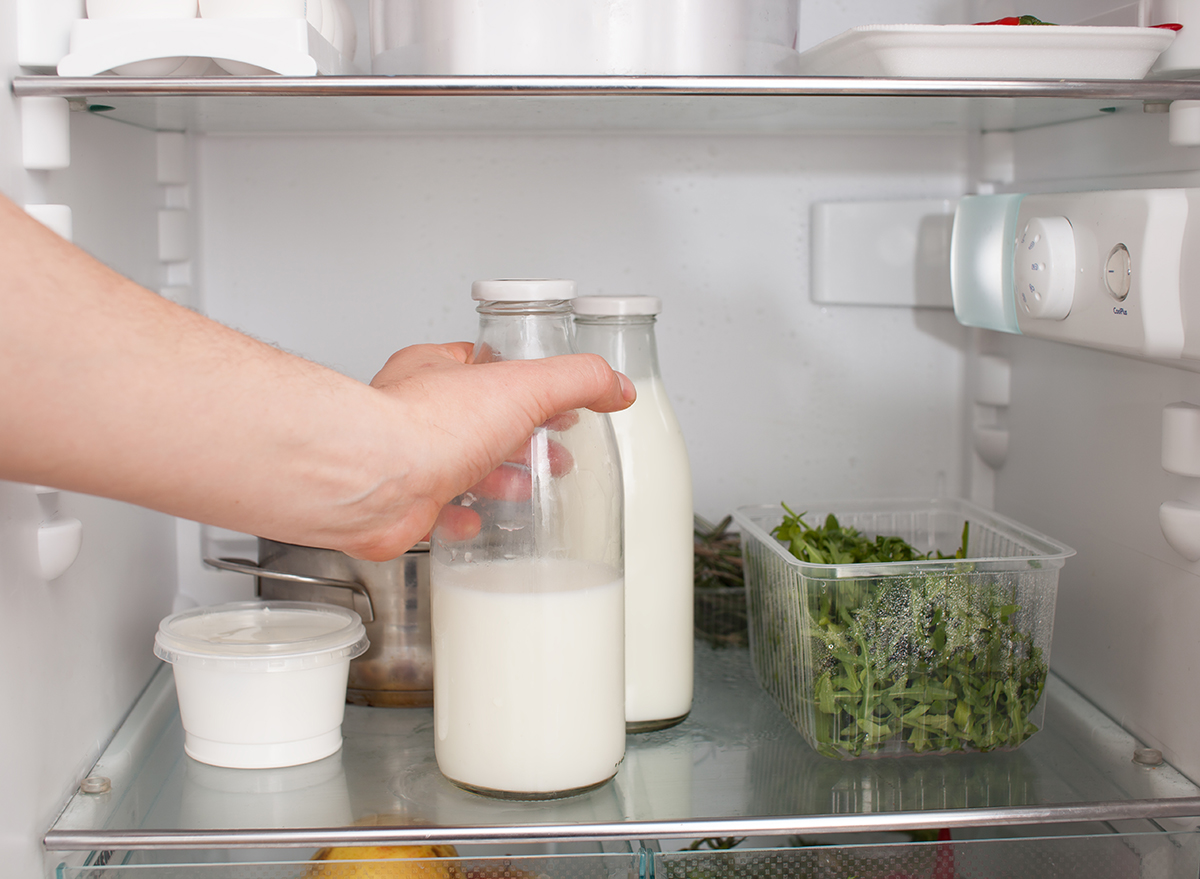 person putting a glass jar of milk in the refrigerator