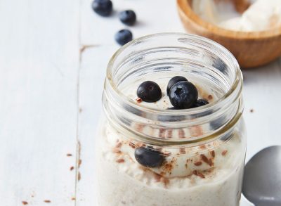 overnight cinnamon roll oats in open glass mason jar with blueberries on wooden tabletop with spoon