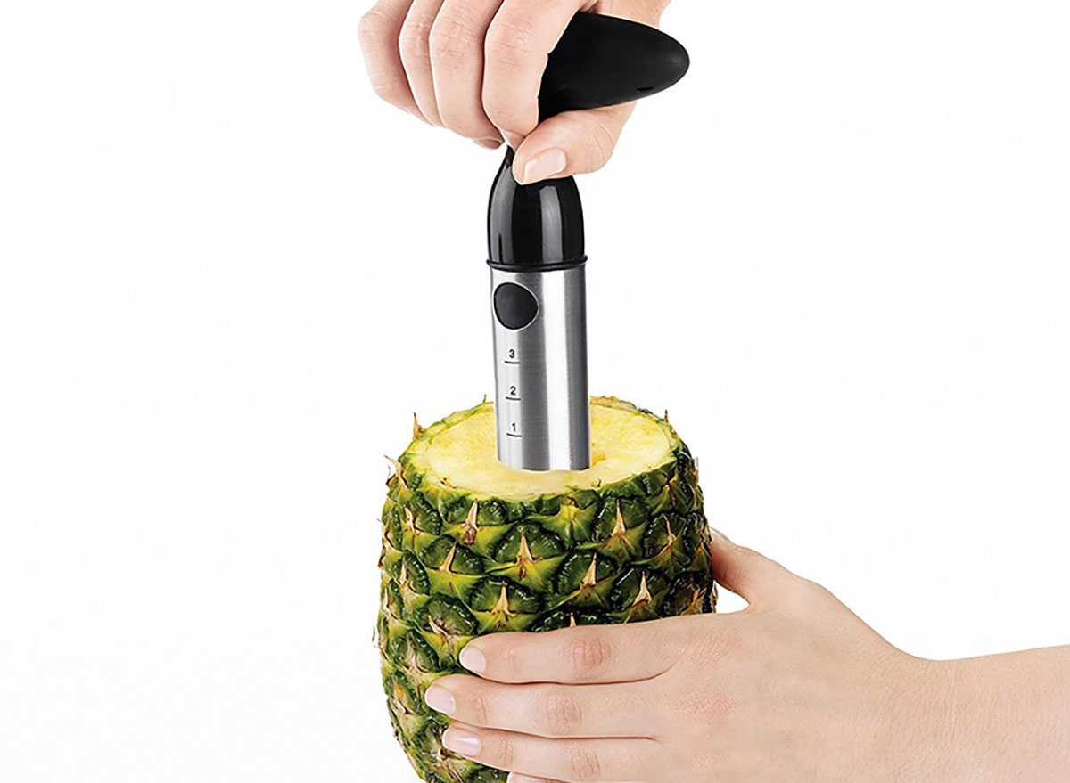 person's hands using oxo pineapple slicer corer with pineapple