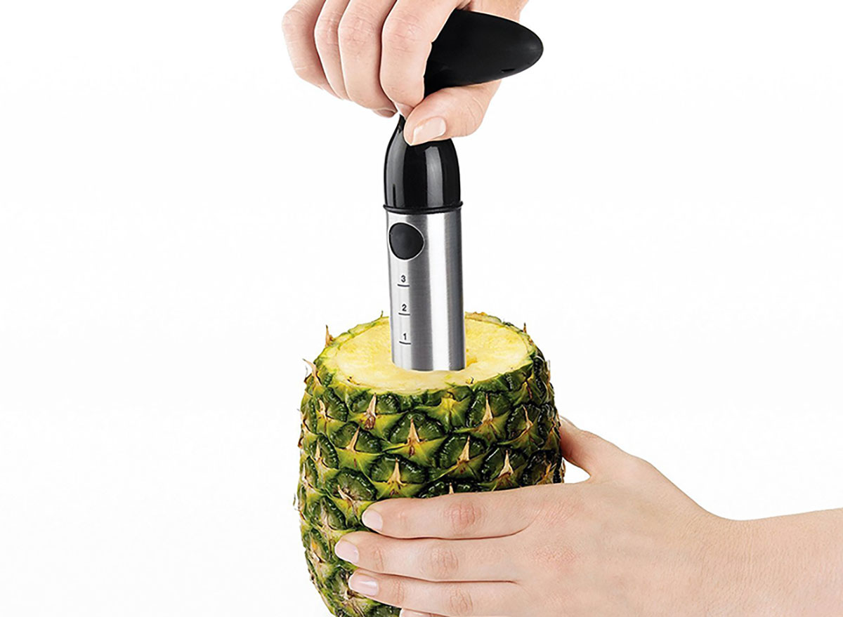 person's hands using oxo pineapple slicer corer with pineapple