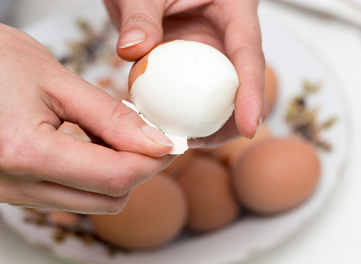 peeling hard boiled eggs with hands easily over a bowl of eggs to be peeled