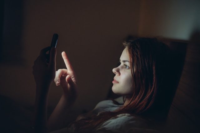 Girl in a dark room on the bed with the phone