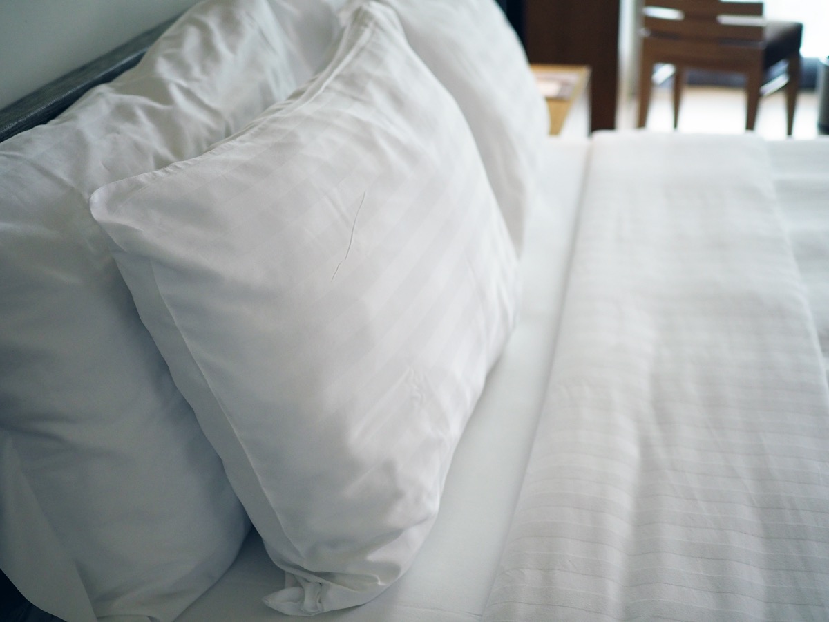 Big white soft pillows on a white luxury cozy bed with clean white sheets.