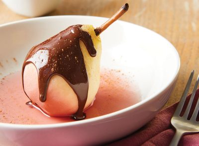 poached pear with spiced chocolate sauce in white bowl with fork
