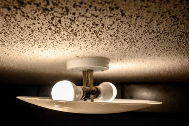 popcorn textured ceiling with LED bulb light fixture and glass cover.