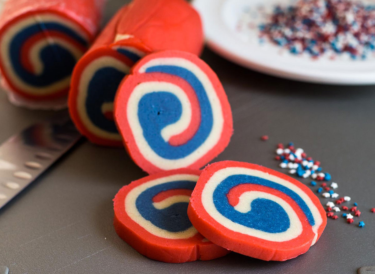 red white and blue pinwheel cookies with star sprinkles on black cutting board