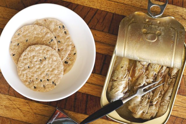 Sardines in tin next to flax crackers