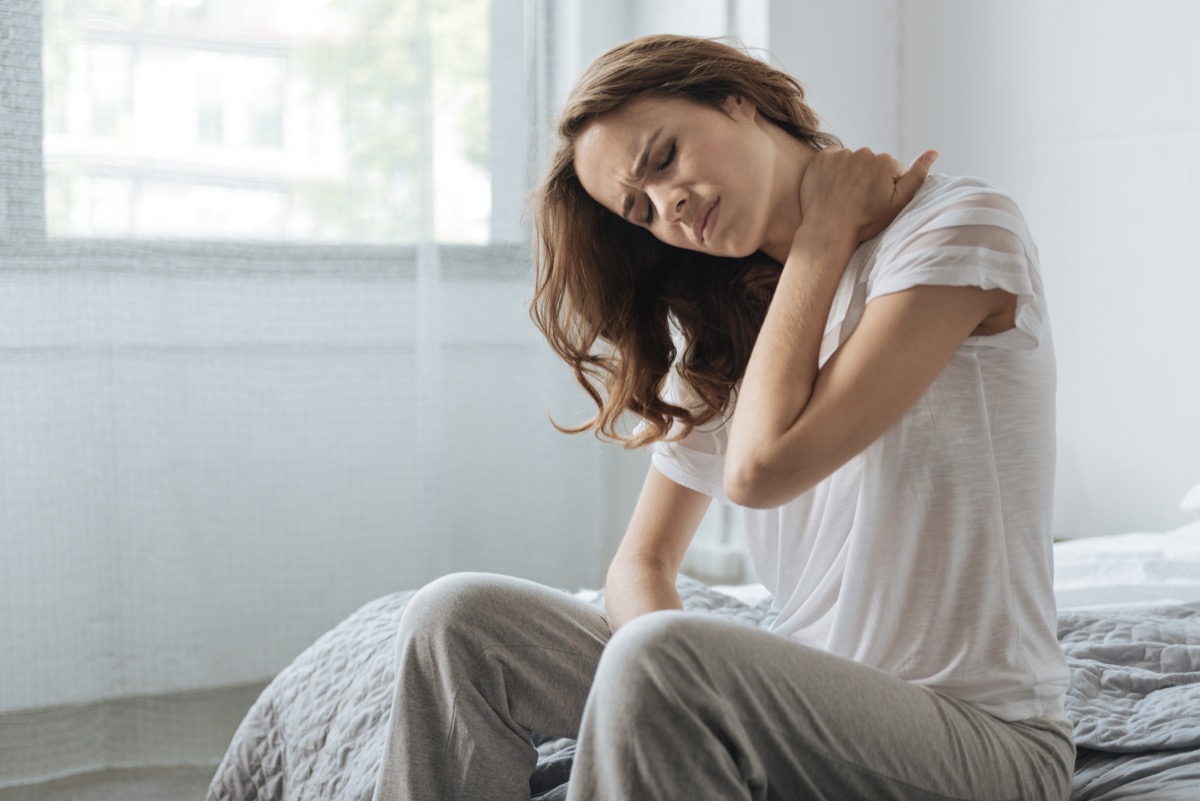 Moody young woman holding her neck