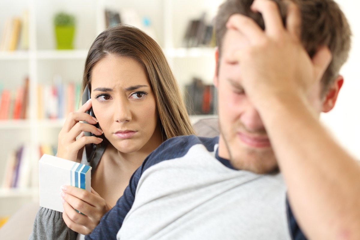 Worried wife calling doctor requesting information sitting on a sofa in the living room
