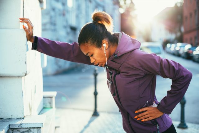 young woman stretching outside while running