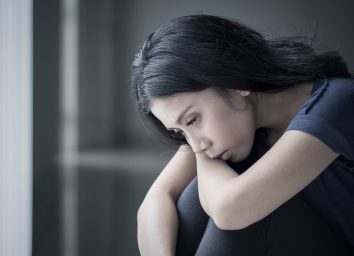 sad woman suffering anorexia while sitting in the black background
