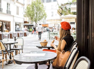 young woman red beret eating french breakfast coffee croissant outdoors at cafe table