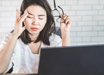 Asian woman worker suffering from eye strain taking off her eyeglasses tired from working on computer screen