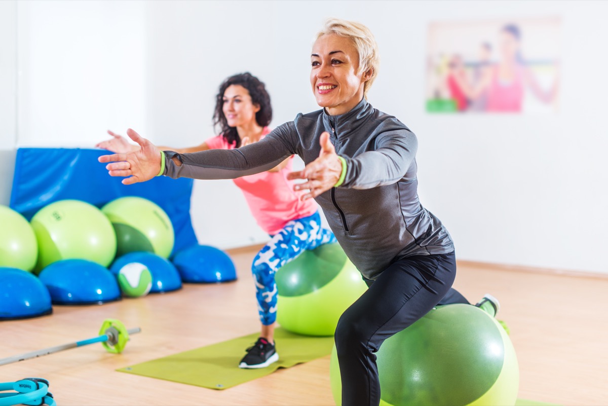 Sporty women doing stretching exercises with fitness stability ball in a sports club
