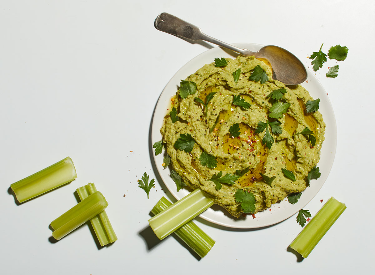bowl of avocado hummus with celery and spoon