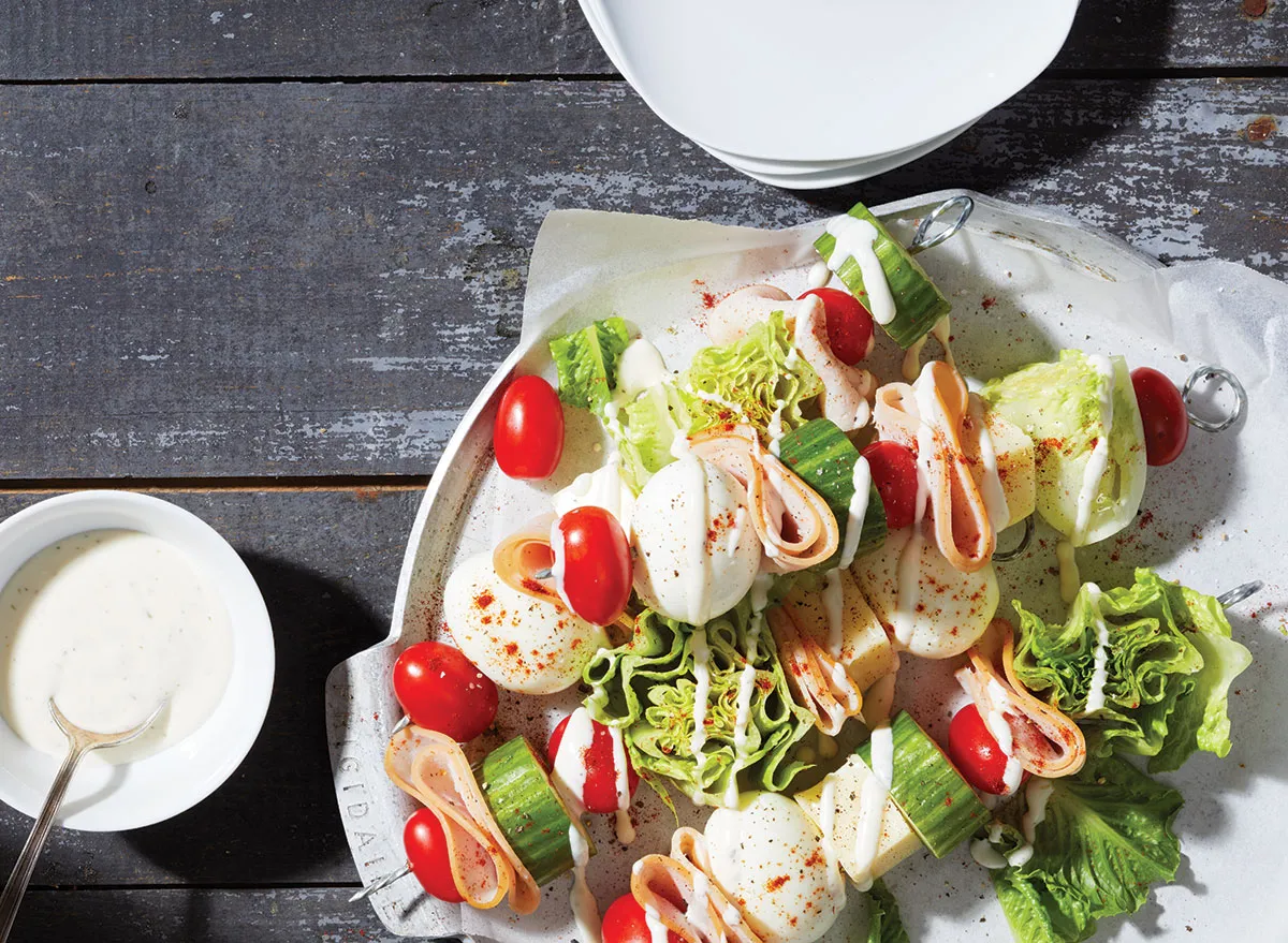 Köche Salateier auf Stöcken mit Joghurt auf weißem Teller und grauem Hintergrund